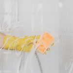 A gloved hand cleans glass with a sponge and soapy water, ensuring hygiene.