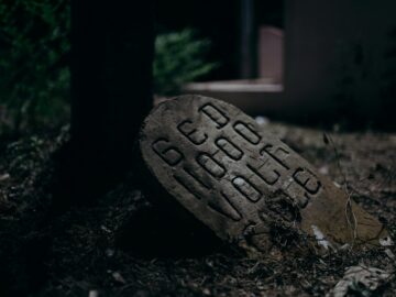 A dimly lit stone marker with bold lettering, creating a mysterious and moody atmosphere.