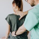 A doctor performs a spine examination on a seated patient at a medical clinic.