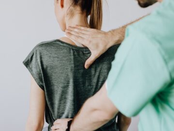 A doctor performs a spine examination on a seated patient at a medical clinic.