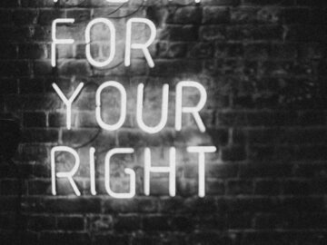 Monochrome neon sign on brick wall with slogan 'Fight for Your Right.' Perfect for motivation and urban themes.