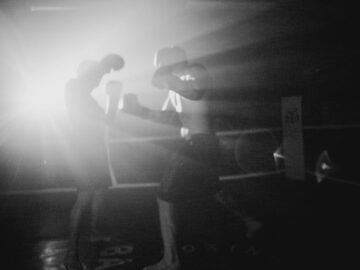 A powerful black and white image of boxers sparring with dramatic lighting in a gym setting.
