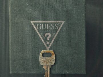 Close-up of a vintage rusty key with the GUESS? logo background, offering an antique charm.