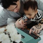 Father teaching curious child to use a vintage typewriter, fostering creativity and learning.