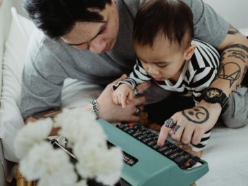 Father teaching curious child to use a vintage typewriter, fostering creativity and learning.