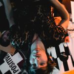 A relaxed musician with an electric guitar and closed eyes surrounded by vinyl records.