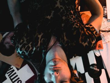 A relaxed musician with an electric guitar and closed eyes surrounded by vinyl records.