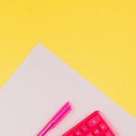 A vibrant pink calculator and pen set on a striking yellow background, perfect for educational themes.