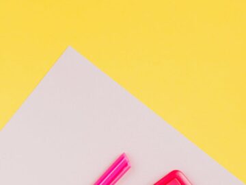 A vibrant pink calculator and pen set on a striking yellow background, perfect for educational themes.