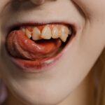 Detailed shot focusing on a mouth with visible fangs and tongue, evoking a vampire aesthetic.