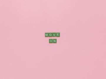 Inspirational text "Move On" spelled with green tiles on a pink background. Minimalist design, perfect for motivation.
