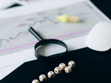 Conceptual still life of business documents, charts, and magnifying glass focusing on risk analysis.