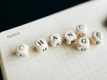 Close-up of letter dice spelling 'change' on a grid notepad, symbolizing transformation.