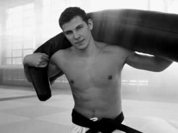 A young male martial artist training indoors with a punching bag.
