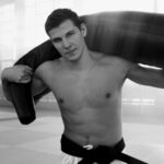 A young male martial artist training indoors with a punching bag.