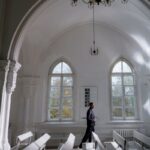 A serene interior of a church with a person in thoughtful prayer, illuminated by soft natural light.