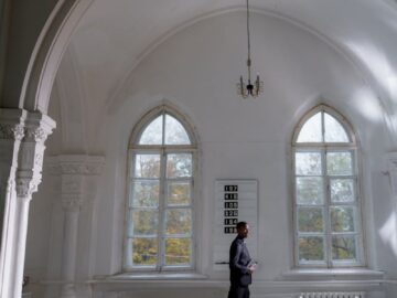 A serene interior of a church with a person in thoughtful prayer, illuminated by soft natural light.
