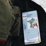 Detailed view of a hiking map on snowy terrain with a backpack nearby, ideal for adventure themes.