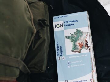 Detailed view of a hiking map on snowy terrain with a backpack nearby, ideal for adventure themes.