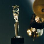 A sleek silver trophy with a star top, beautifully reflecting on a dark surface, symbolizing achievement and success.