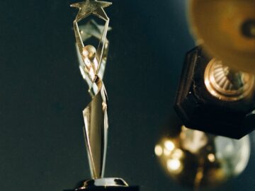 A sleek silver trophy with a star top, beautifully reflecting on a dark surface, symbolizing achievement and success.