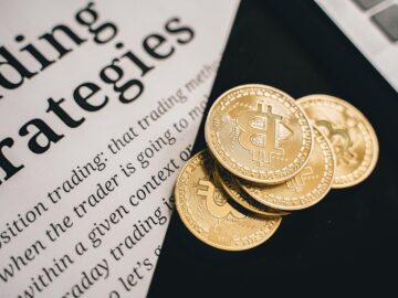 Close-up of gold Bitcoin coins on a trading document, symbolizing investment and cryptocurrency market strategies.