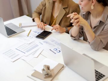 Two professionals collaborating on financial documents in a modern office setting.