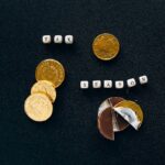 Black background highlighting gold coins and chocolate representing a tax season concept.