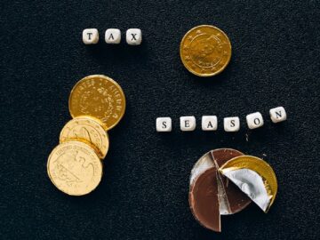 Black background highlighting gold coins and chocolate representing a tax season concept.
