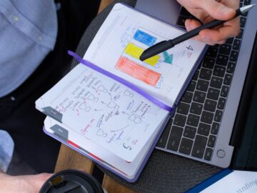 Man working with notes and laptop over a coffee break, analyzing charts.