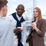 Diverse professionals sharing a coffee break at the office, enjoying conversation.