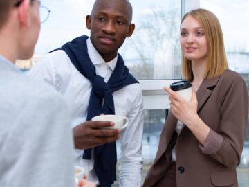 Diverse professionals sharing a coffee break at the office, enjoying conversation.