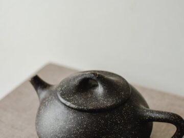 A close-up of a black teapot with a modern minimalist design, perfect for contemporary interiors.