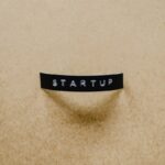 A minimalist image of the word 'STARTUP' on a beige textured surface conveying creative business concepts.