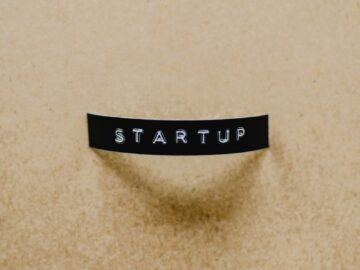 A minimalist image of the word 'STARTUP' on a beige textured surface conveying creative business concepts.