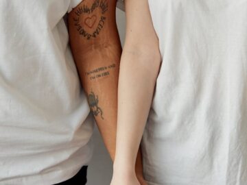 A close shot of a couple holding hands, wearing matching white shirts and black pants, symbolizing unity.