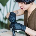 Tattoo artist concentrating while working in a studio with gloves. Ethnic woman indoors.
