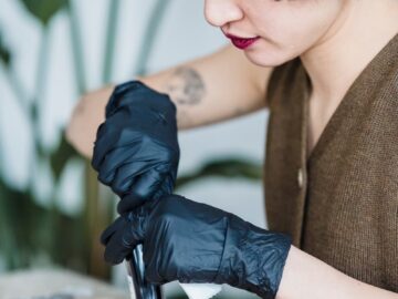 Tattoo artist concentrating while working in a studio with gloves. Ethnic woman indoors.