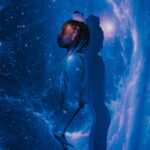 A woman stands against a galaxy projection with a serene profile, embodying cosmic dreams.