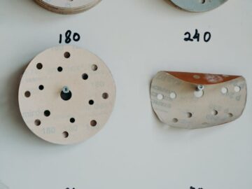 A variety of sandpaper discs with different grit sizes neatly arranged on a workshop wall.