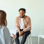 A therapy session in a modern office setting with a counselor and a client engaged in conversation.