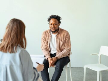 A therapy session in a modern office setting with a counselor and a client engaged in conversation.