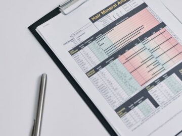 A hair mineral analysis report displayed on a clipboard photographed from above, with a pen nearby.