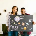 A mother and son proudly display their handmade solar system project.
