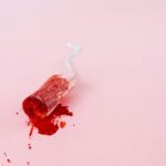 Close-up image of a blood-stained tampon on a pink background symbolizing menstruation.
