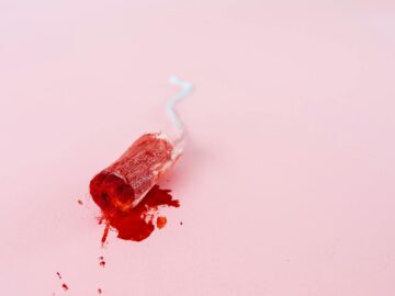 Close-up image of a blood-stained tampon on a pink background symbolizing menstruation.