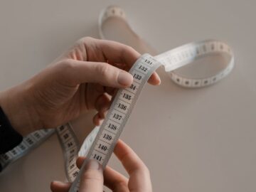 Close-up of hands holding a white measuring tape, ideal for sewing concepts.