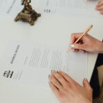 Close-up of hands signing a divorce decree document on a desk, showcasing legal process.
