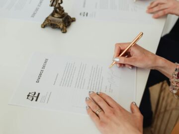 Close-up of hands signing a divorce decree document on a desk, showcasing legal process.