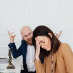 Two colleagues in a law office engaging in a tense discussion, showcasing frustration and stress.